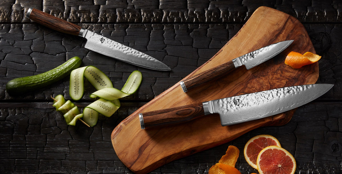 Three Shun Premier knives with hammered Damascus blades on an olive wood cutting board